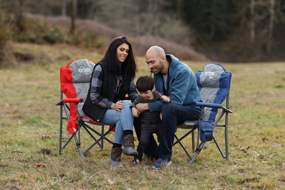 A family enjoying the outdoors while sitting on Gobi Heat’s heated camping chairs, bundled up and smiling, showcasing comfort, warmth, and quality time in cold weather conditions.
