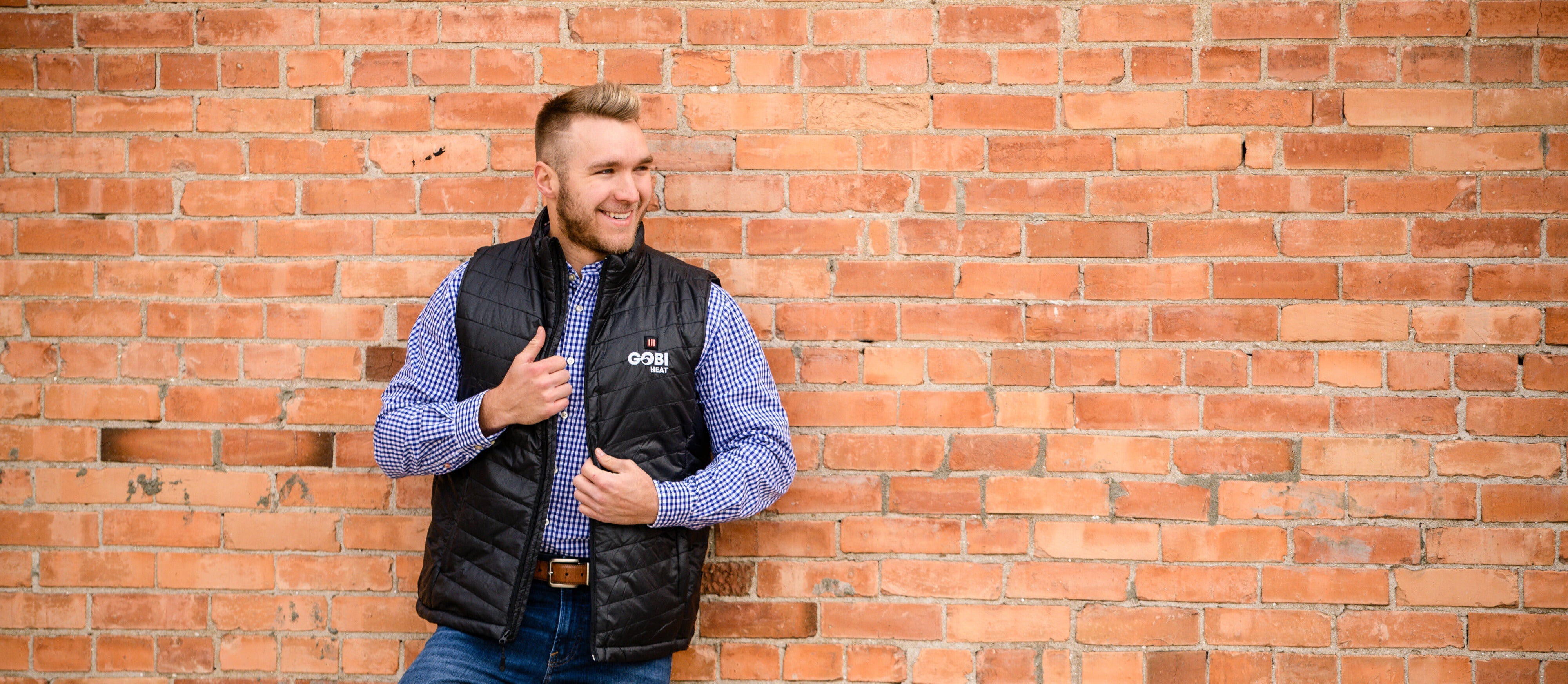 man leaning against brick wall wearing a gobi heat heated vest