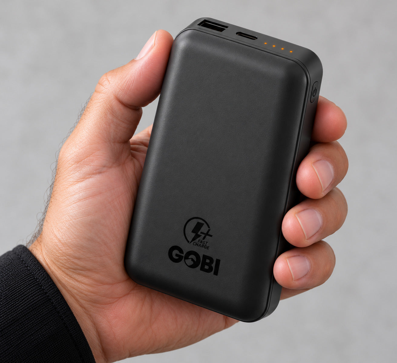 A hand holding the GOBI 6500-PD battery, with the USB-A and USB-C ports, charge indicator lights, and side power button visible.